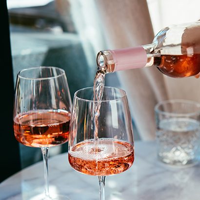 Pouring rose wine at a dinner party with friends in a bar or restaurant.